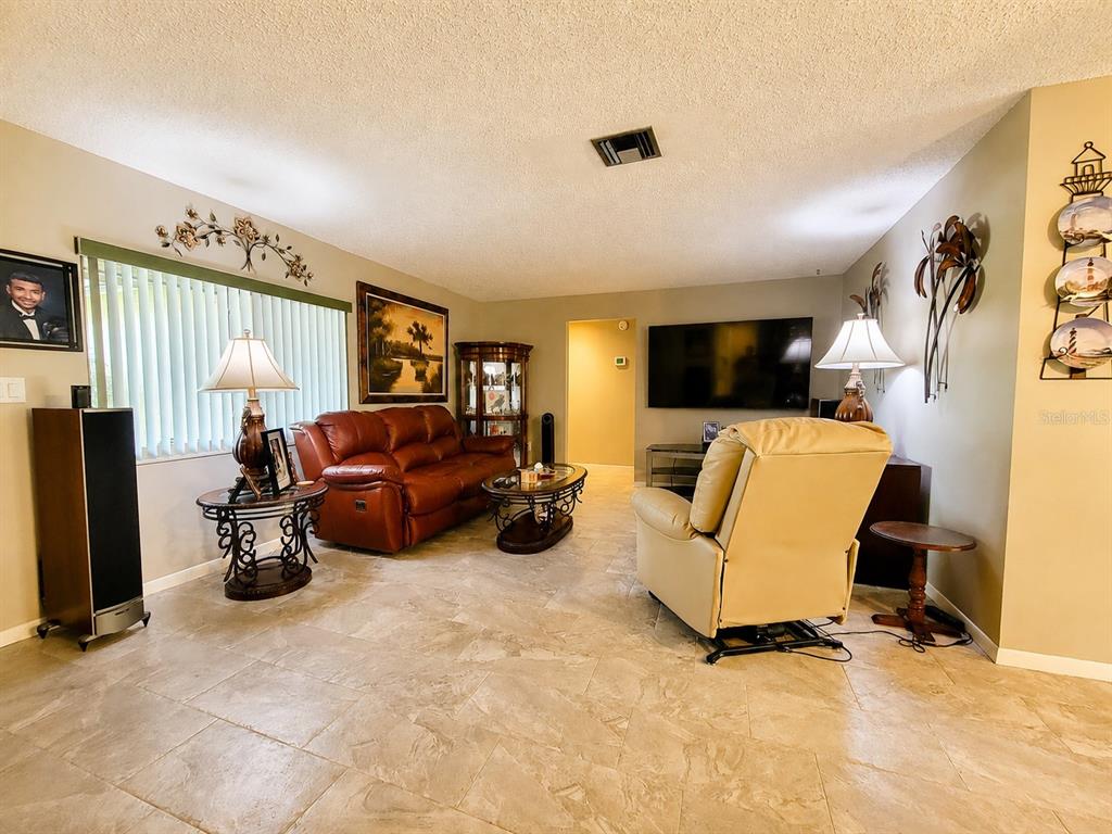 A living room features tile flooring, a leather sofa, a recliner, and a wall-mounted television — 9391 118TH LANE, SEMINOLE, FL
