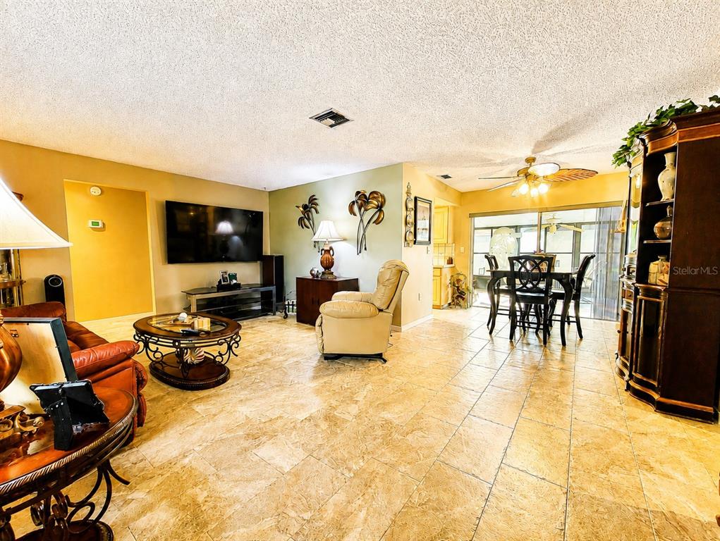 A living and dining area features tile flooring, a ceiling fan, and a wall-mounted television — 9391 118TH LANE, SEMINOLE, FL