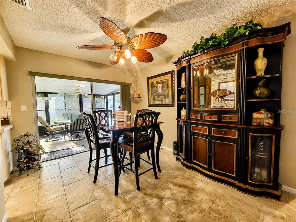A dining room features a dark wood hutch, a leaf-shaped ceiling fan, and tile flooring — 9391 118TH LANE, SEMINOLE, FL