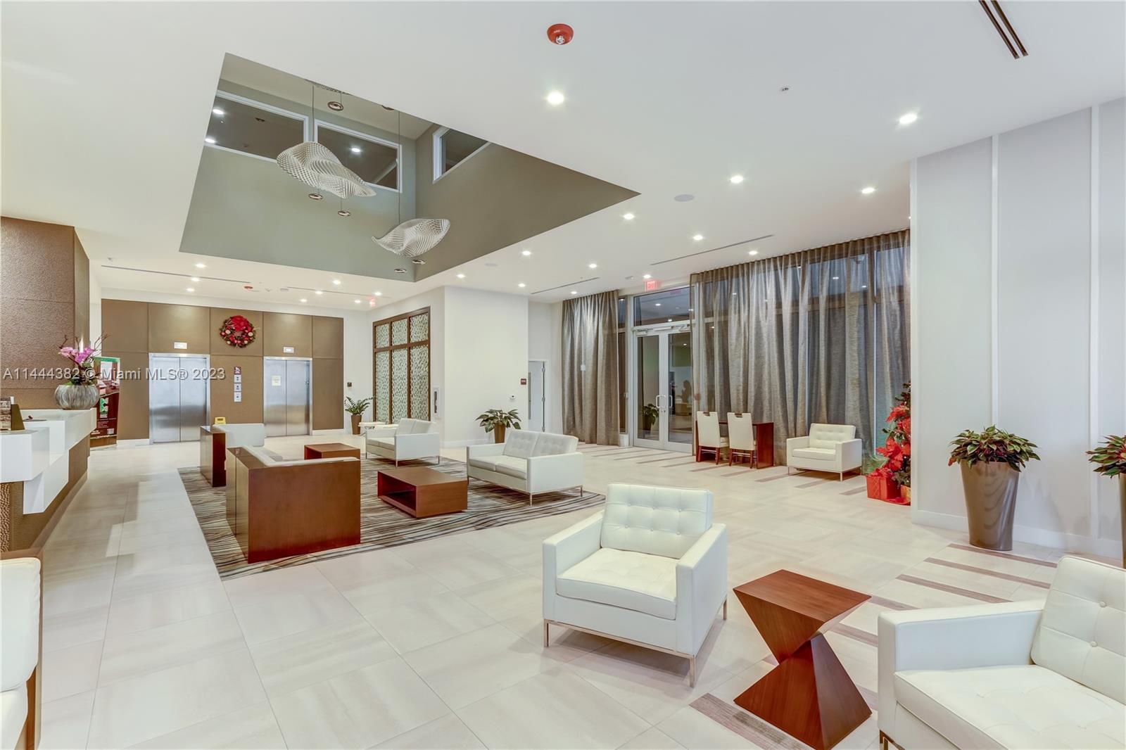 A modern lobby features white tile floors, white leather seating, and a recessed ceiling area — 7825 NW 107th Ave # 816, Doral FL 33178, DORAL, FL