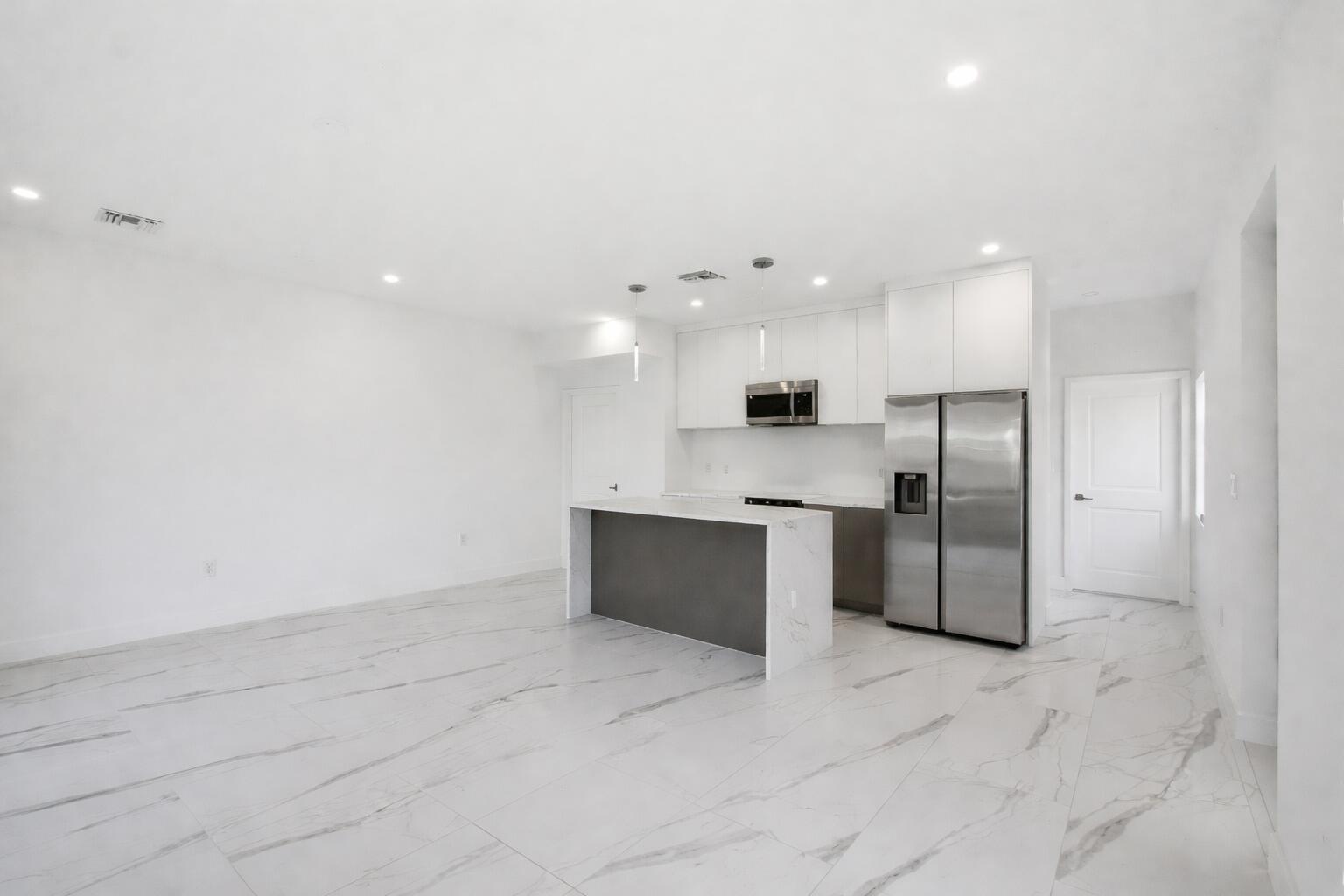 A modern kitchen features white cabinets, stainless steel appliances, and a marble-topped island — 1548 NW 1st Avenue, Pompano Beach FL 33060, POMPANO BEACH, FL