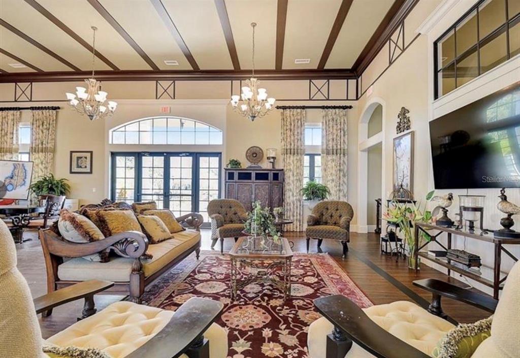A spacious living room features high coffered ceilings, chandeliers, a large rug, and dark wood floors — 808 WATERFERN TRAIL DRIVE, AUBURNDALE, FL