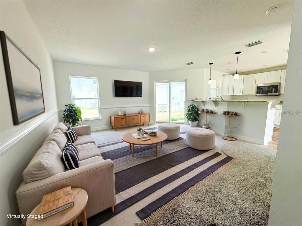 A living room with a sofa, coffee table, and kitchen counter in an open floor plan — 222 CARPENTERS WAY UNIT 67, LAKELAND, FL