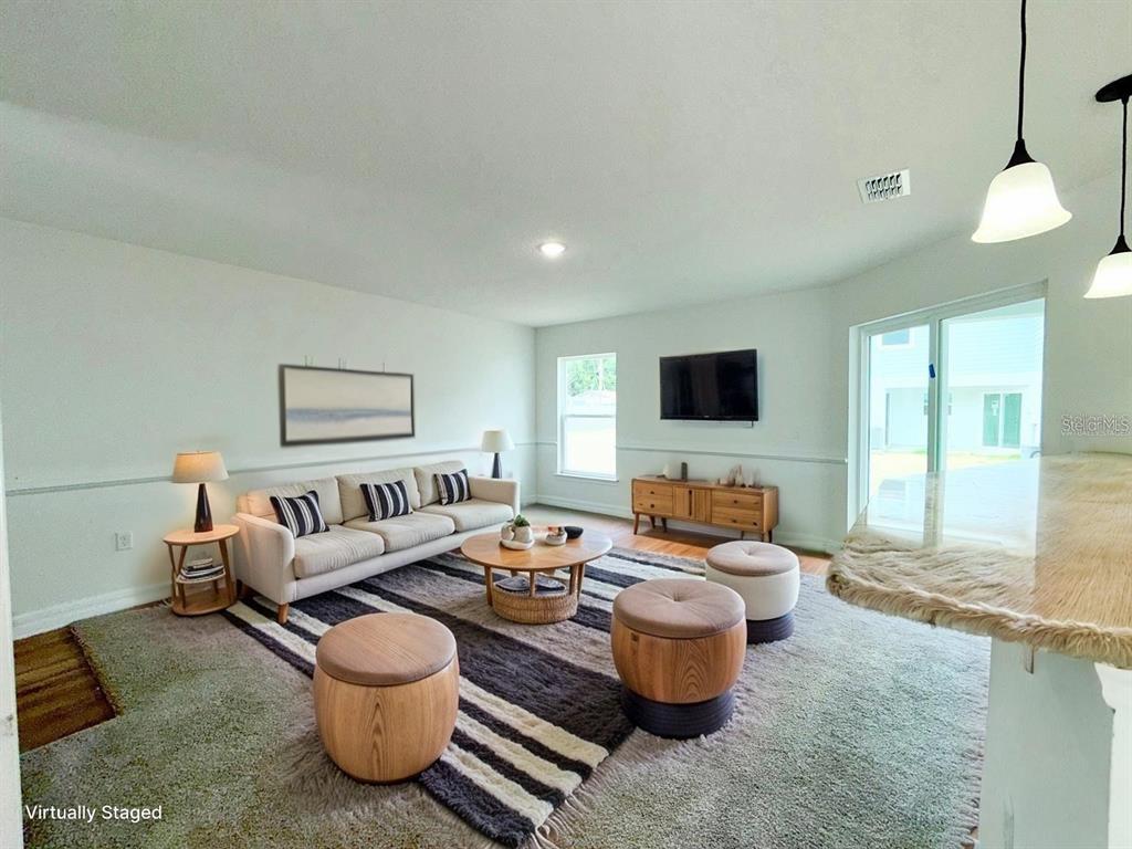 This virtually staged living room features a sofa, coffee table, area rug, and television — 222 CARPENTERS WAY UNIT 67, LAKELAND, FL