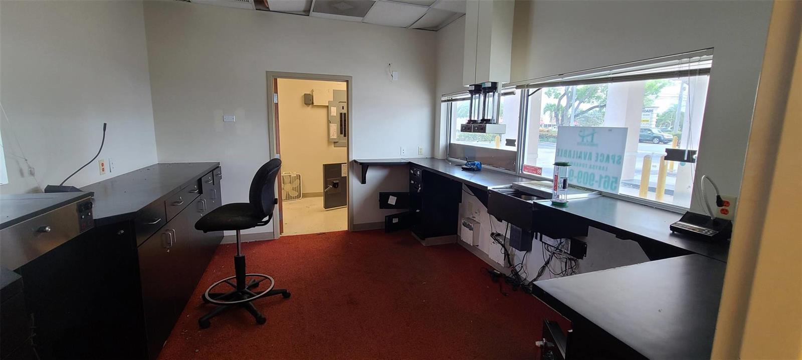 An office space with red carpeting, black built-in desks, and a window overlooking a parking lot — 5300 Coconut Creek Parkway, Margate FL 33063, MARGATE, FL