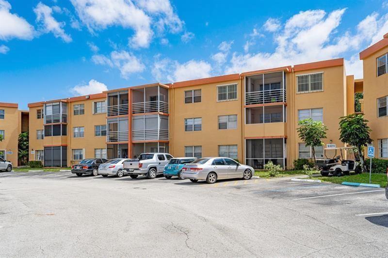 A multi-story apartment building with tan stucco walls and screened balconies sits above a parking lot — 4324 NW 9th Avenue # 3c, Pompano Beach FL 33064, POMPANO BEACH, FL