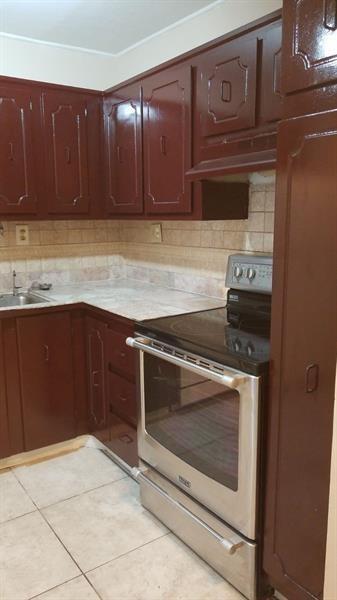 A kitchen features dark brown cabinets, a stainless steel stove, and light-colored tiled countertops — 4324 NW 9th Avenue # 3c, Pompano Beach FL 33064, POMPANO BEACH, FL