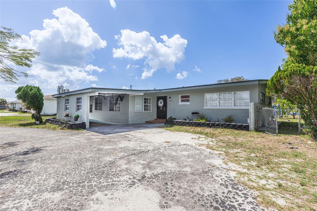 A single-story gray house with a carport and a large, weathered asphalt driveway — 3425 HARBOR BOULEVARD, PORT CHARLOTTE, FL