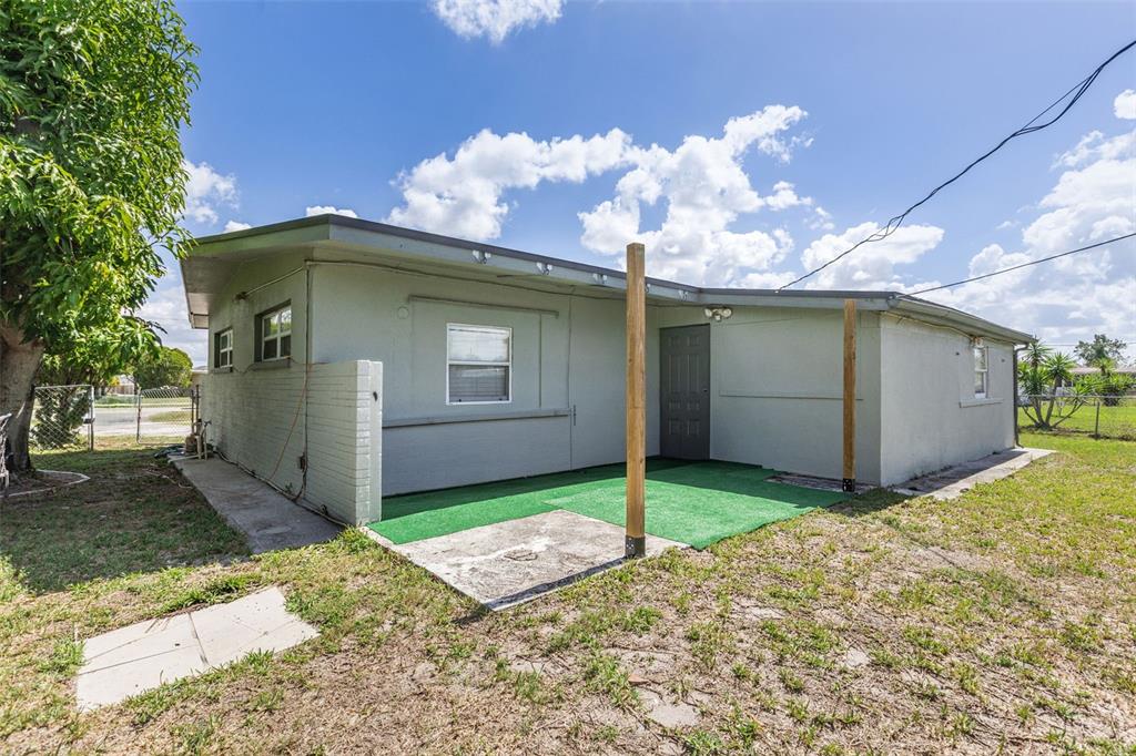 The exterior of a single-story house features a green turf patio and two wooden posts — 3425 HARBOR BOULEVARD, PORT CHARLOTTE, FL