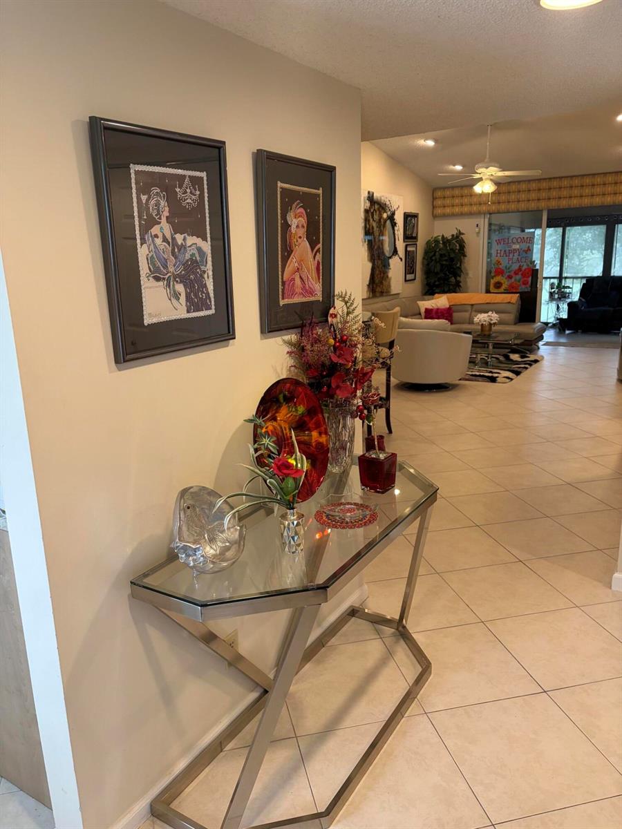 A glass-topped console table sits in a hallway leading to a living room — 7254 Clunie Place # 15005, Delray Beach FL 33446, DELRAY BEACH, FL