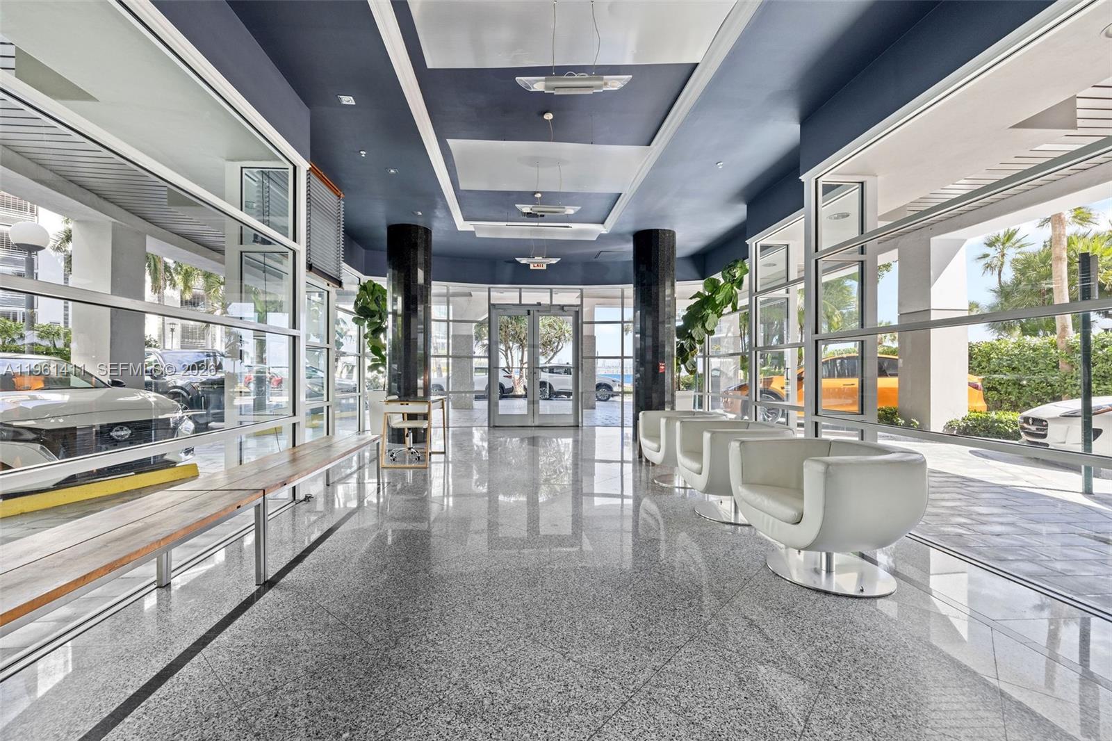 A modern lobby features a polished granite floor, white armchairs, and floor-to-ceiling glass walls — 1402 Brickell Bay Dr # 603, Miami FL 33131, MIAMI, FL