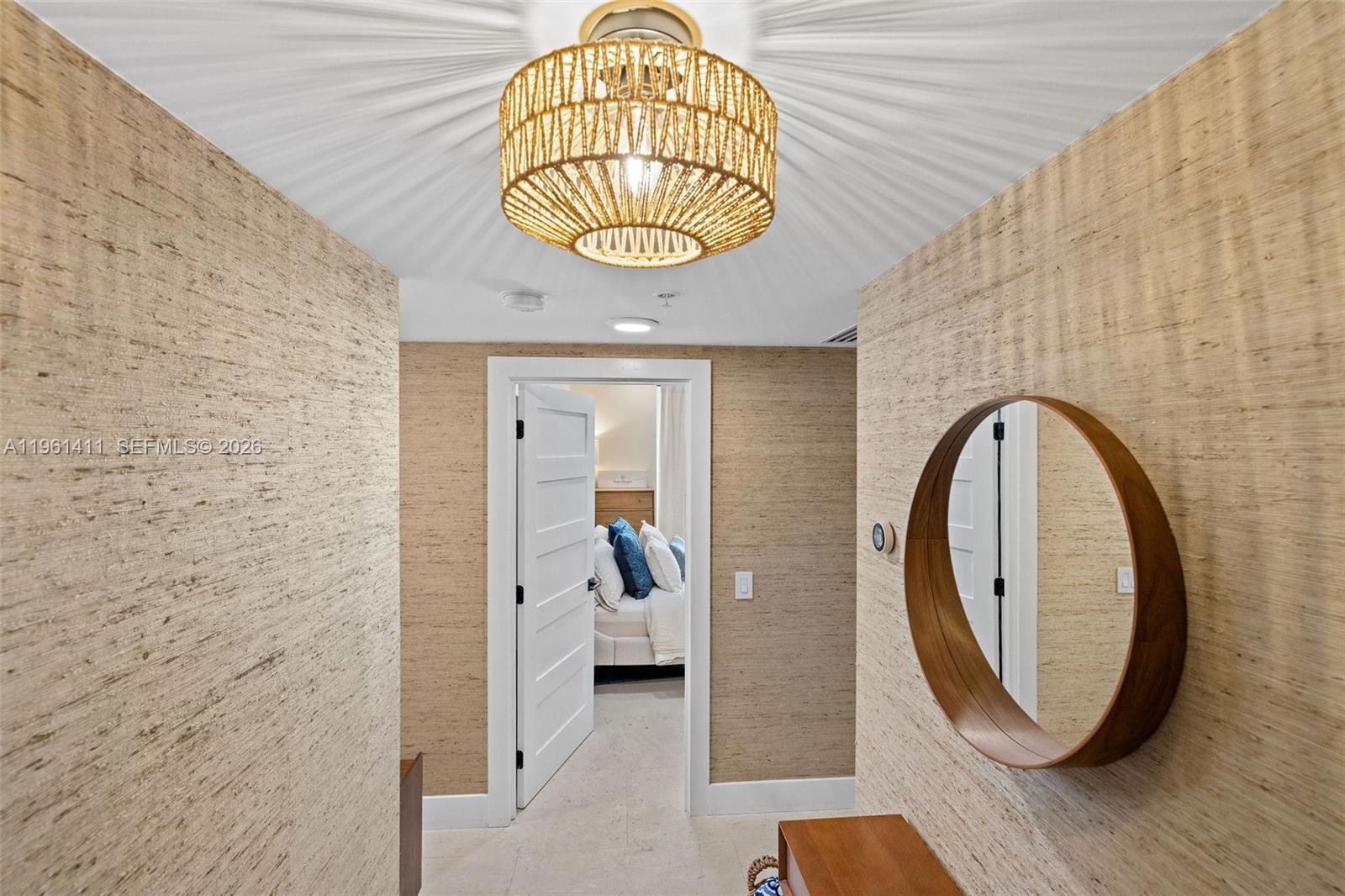 A hallway with textured wallpaper, a round wooden mirror, and a woven drum light fixture — 1402 Brickell Bay Dr # 603, Miami FL 33131, MIAMI, FL