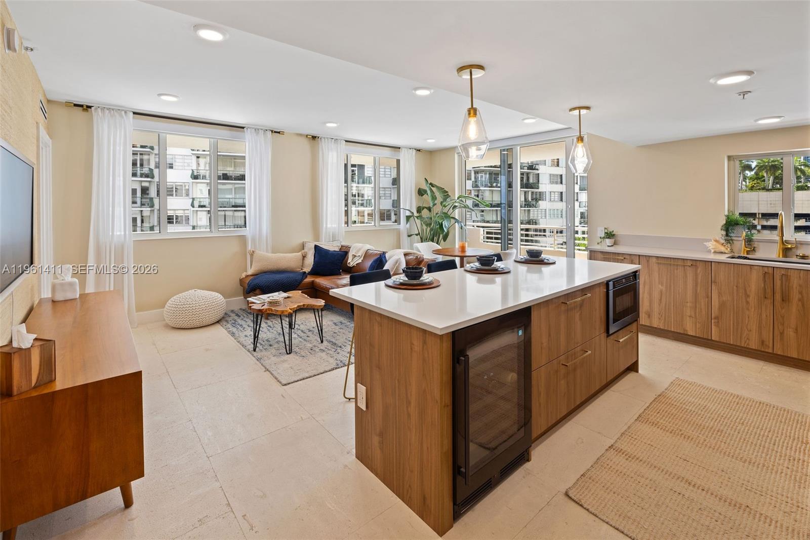 An open-concept kitchen and living area features wood cabinetry, a quartz island, and tile flooring — 1402 Brickell Bay Dr # 603, Miami FL 33131, MIAMI, FL