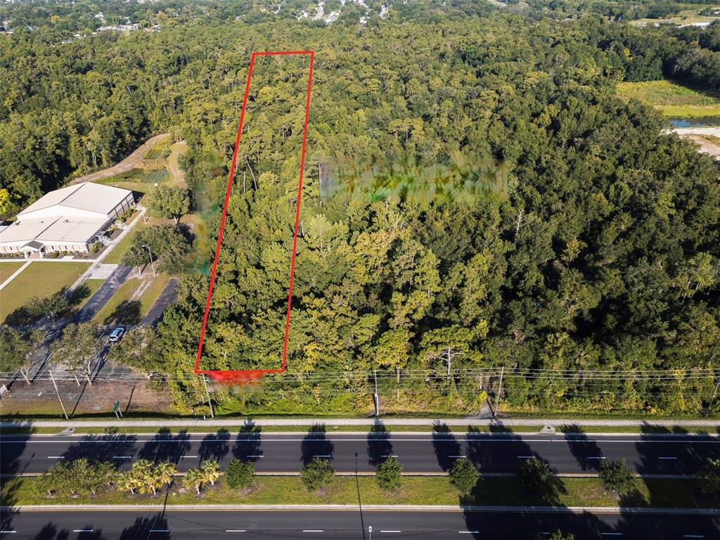 An aerial view shows a rectangular, wooded plot of land outlined in red near a road — 2310 ROUSE ROAD, ORLANDO, FL