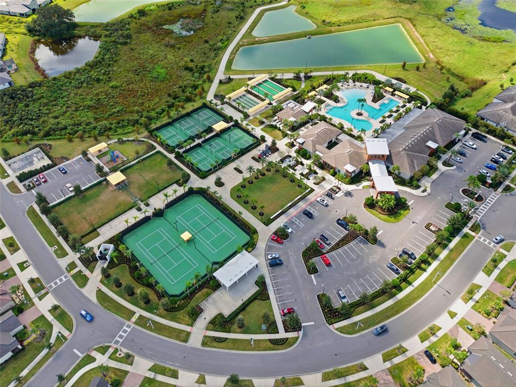 Aerial view of a community center featuring tennis courts, a swimming pool, and parking lots — 31524 MAGNA GOLF LOOP, SAN ANTONIO, FL