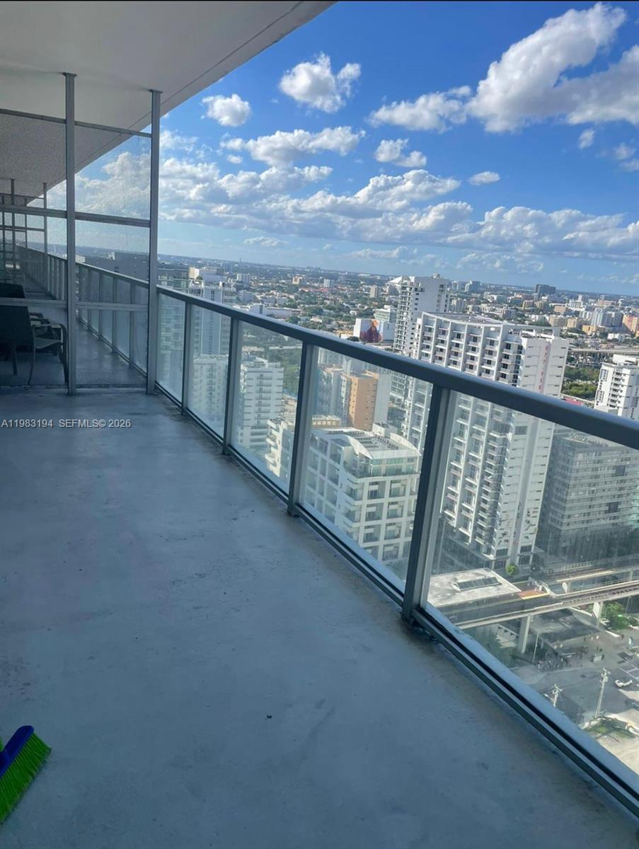 A high-rise balcony with a glass railing overlooks a dense urban cityscape under a sky — 1111 SW 1st Ave, Miami FL 33130, MIAMI, FL