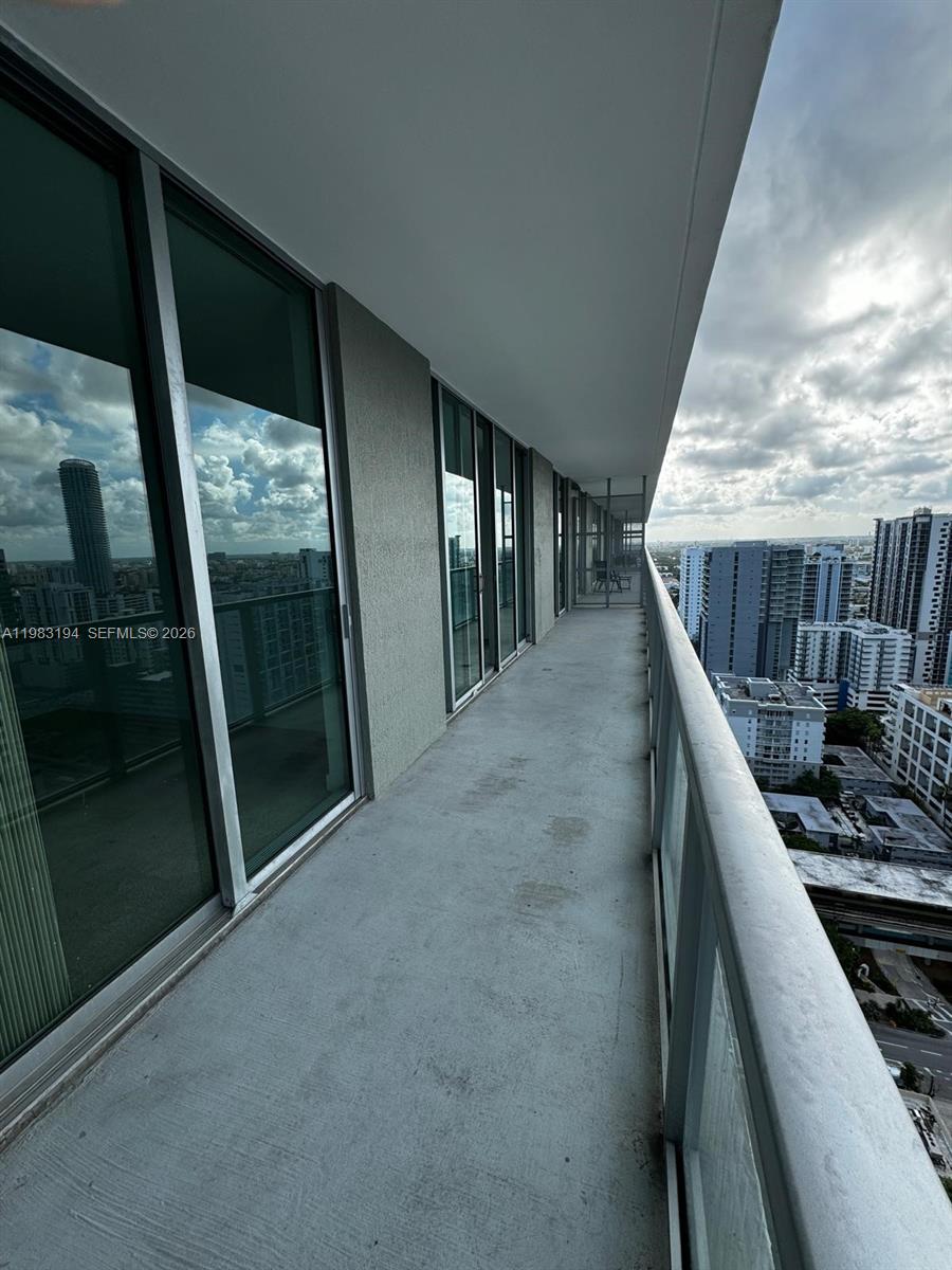 A long, narrow balcony with glass railings overlooks a city skyline — 1111 SW 1st Ave, Miami FL 33130, MIAMI, FL