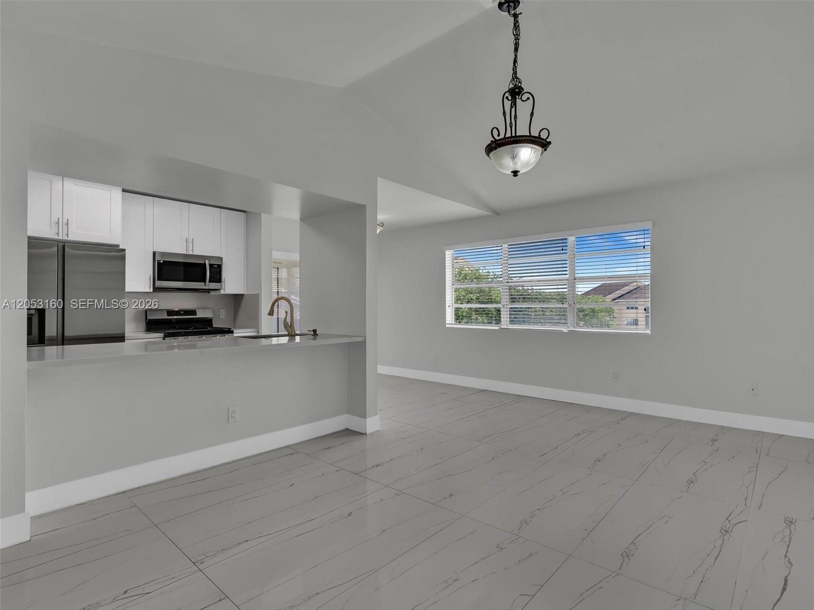 A kitchen with white cabinets and stainless appliances opens to a dining area with tile — 15325 SW 106th Ter # 636, Miami FL 33196, MIAMI, FL