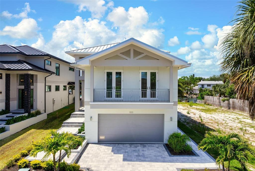 A modern two-story house with a gray garage door and a second-floor balcony — 533 VENICE LANE, SARASOTA, FL