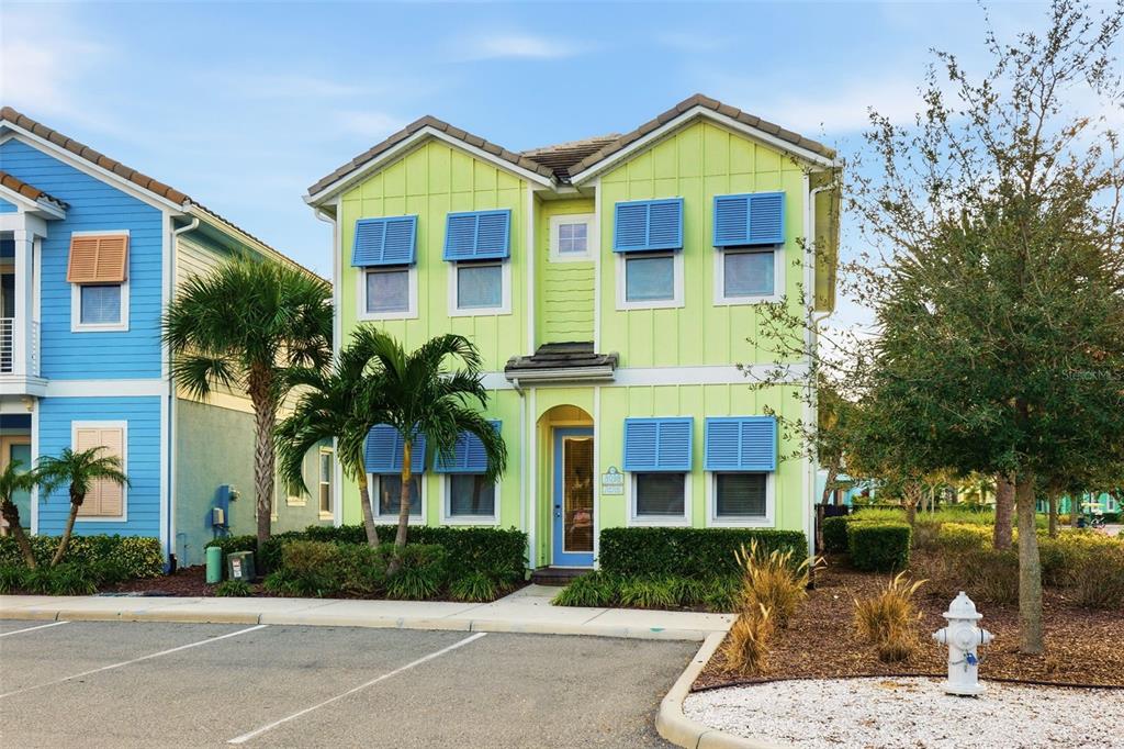 A two-story lime green house with blue shutters and a front door stands near parking — 8098 KNEE DEEP ROAD, KISSIMMEE, FL