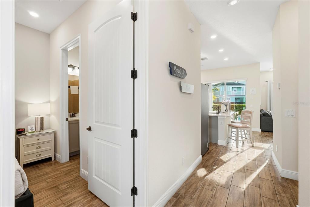 A hallway with wood-look tile flooring leads to a kitchen with a breakfast bar — 8098 KNEE DEEP ROAD, KISSIMMEE, FL