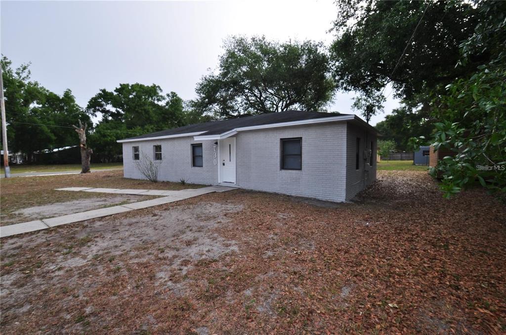 A single-story gray brick house with a white front door and a dark shingled roof — 730 28TH STREET NW, WINTER HAVEN, FL