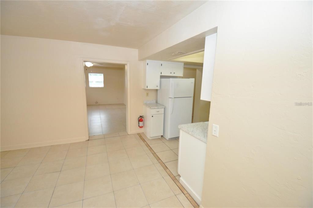 A kitchen area with white cabinets, a white refrigerator, and light-colored tile flooring — 730 28TH STREET NW, WINTER HAVEN, FL
