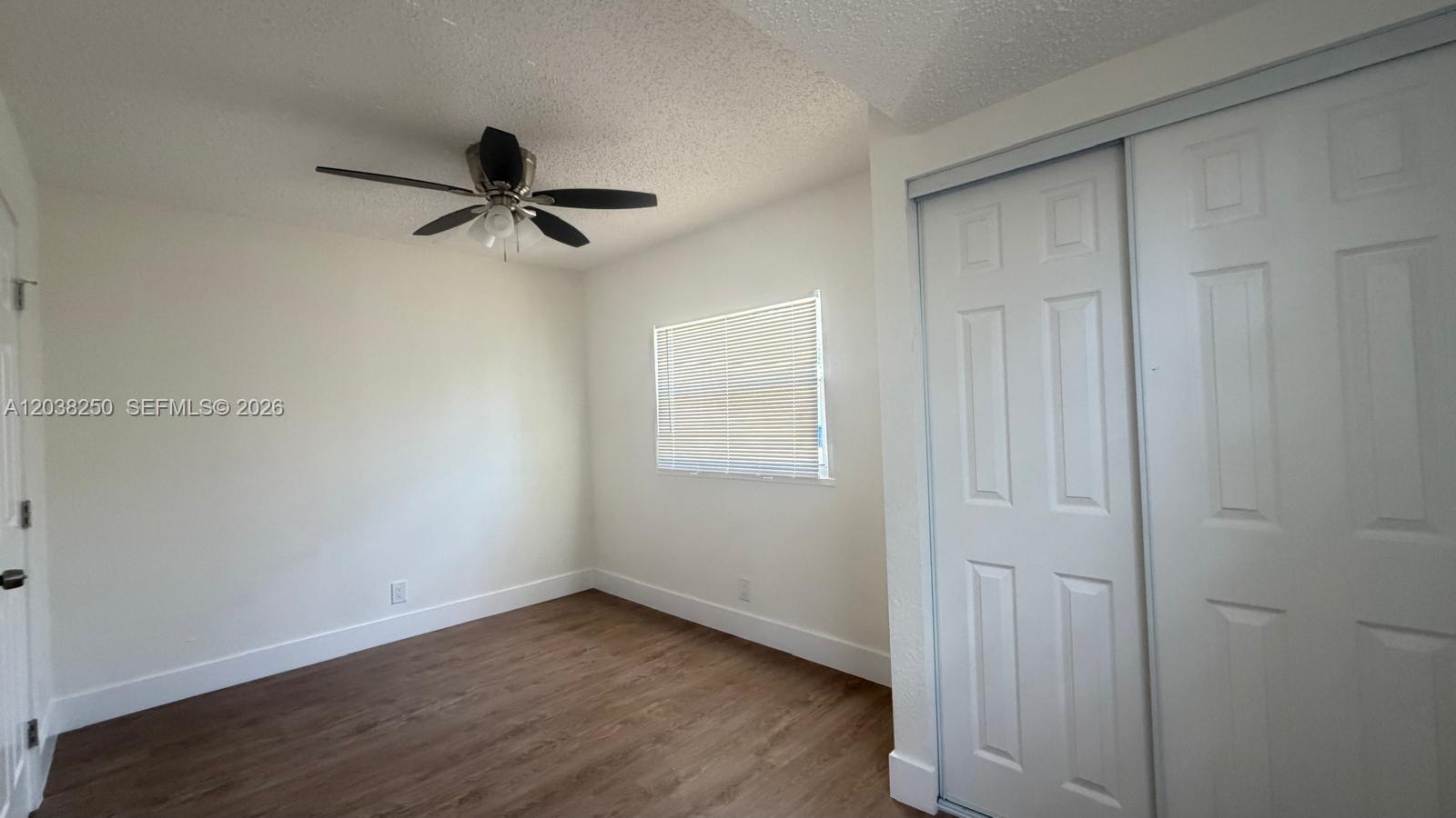 An empty bedroom features white walls, wood-look flooring, a ceiling fan, and a sliding closet — 2580 NW 62nd Ave, Margate FL 33063, MARGATE, FL