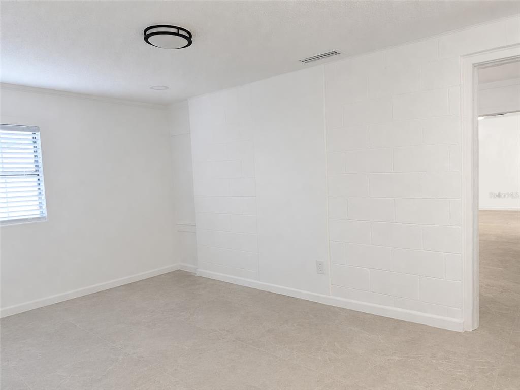 A room with white painted block walls, light tile flooring, and a doorway leading elsewhere — 111 PAGE STREET, ORLANDO, FL