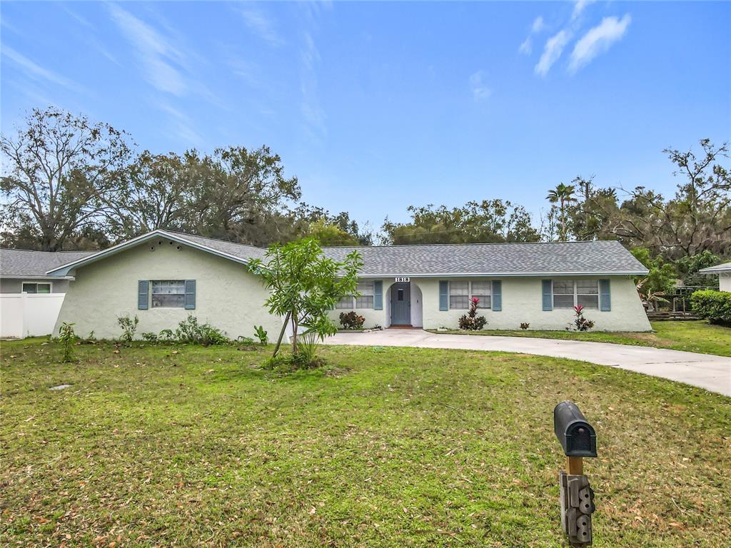 A single-story house with a light green exterior, a gray shingled roof, and a front lawn — 1818 IRLO DRIVE, KISSIMMEE, FL