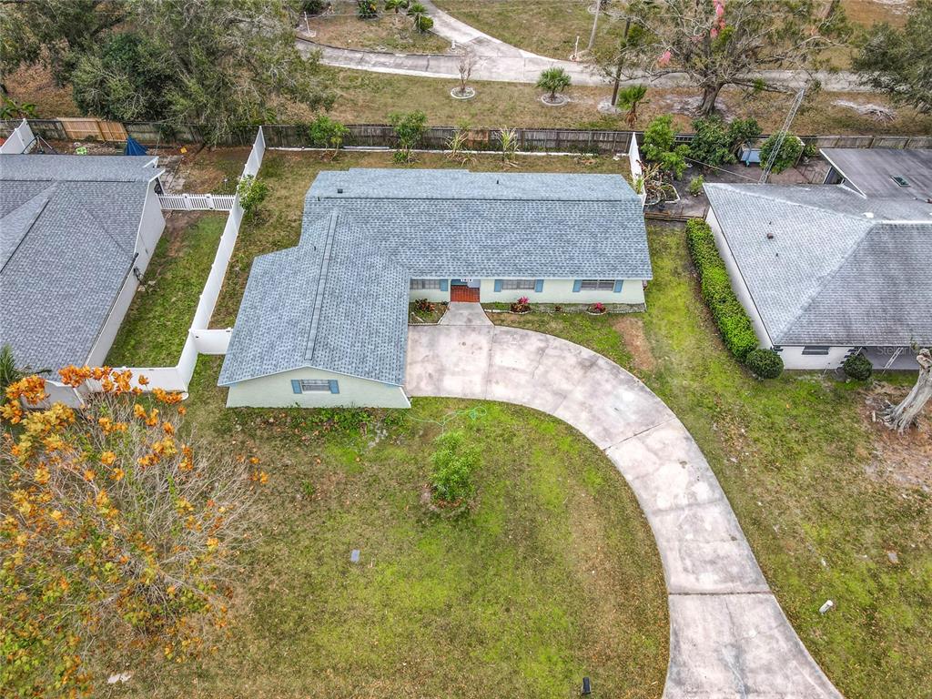 An aerial view shows a single-story house with a gray roof and a curved driveway — 1818 IRLO DRIVE, KISSIMMEE, FL