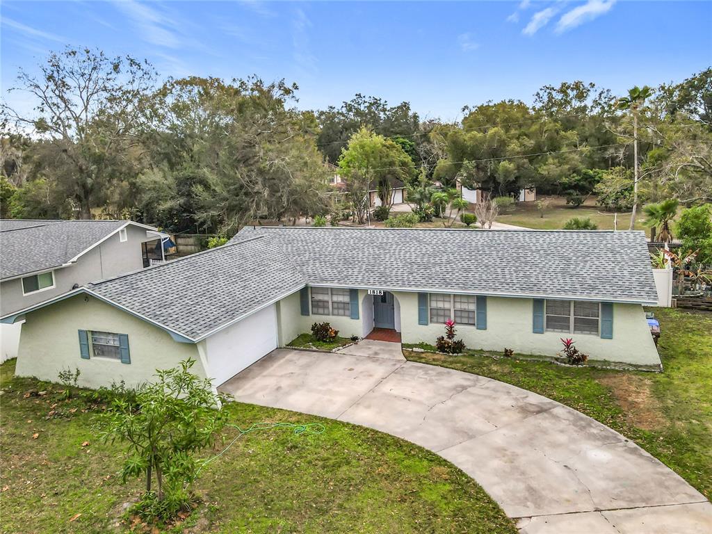 An exterior view of a single-story house with a light green facade and gray roof — 1818 IRLO DRIVE, KISSIMMEE, FL