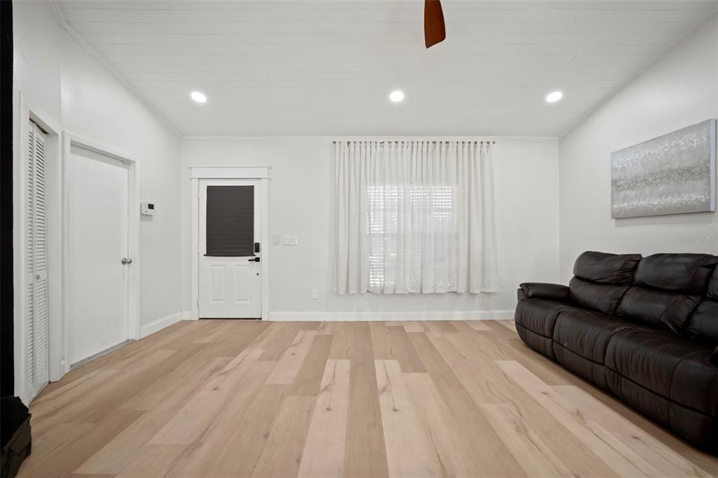 A living room features light wood flooring, white walls, a dark leather sofa, and curtains — 4613 N COUNTRY HILLS COURT, PLANT CITY, FL