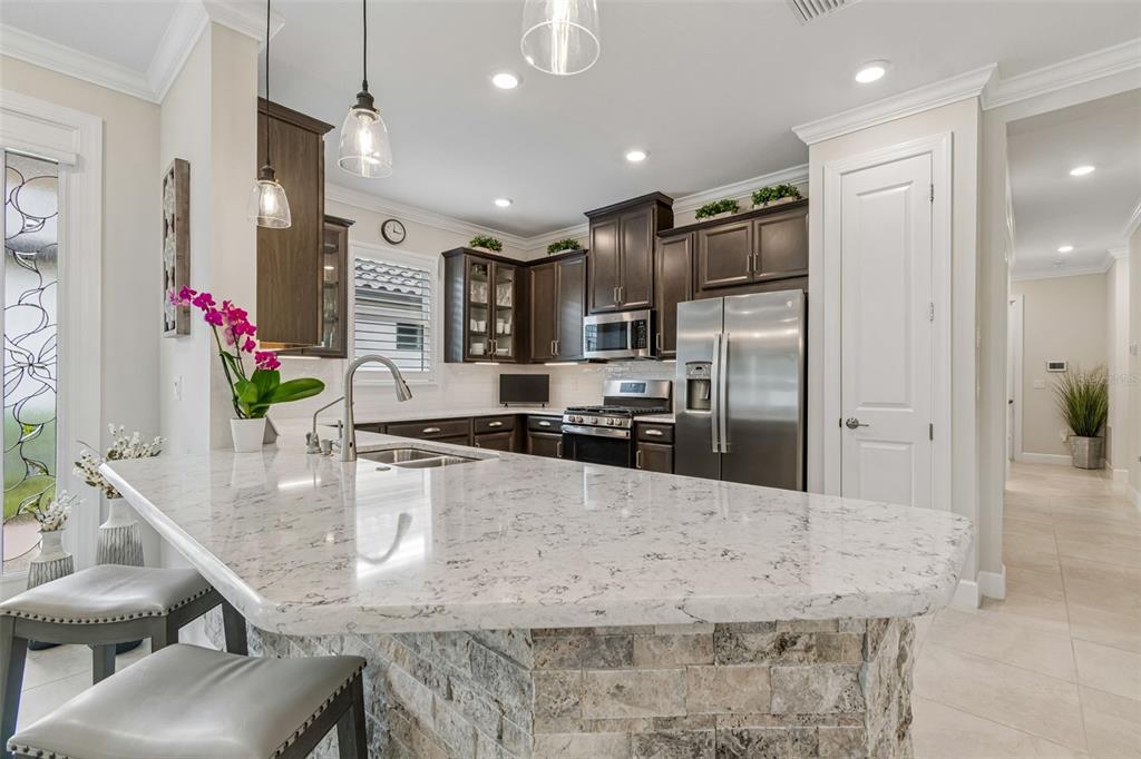 A kitchen with dark wood cabinets, a stone-front island, and white granite countertops — 4534 GAROFALO ROAD, WESLEY CHAPEL, FL