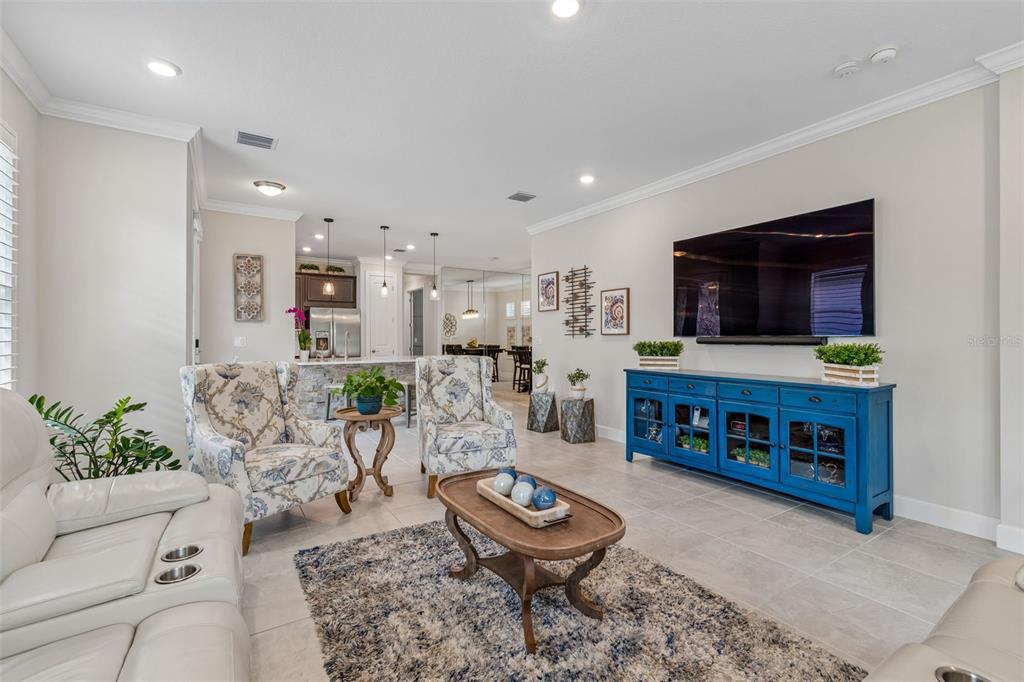A living room features a blue media console, floral armchairs, and a central coffee table — 4534 GAROFALO ROAD, WESLEY CHAPEL, FL