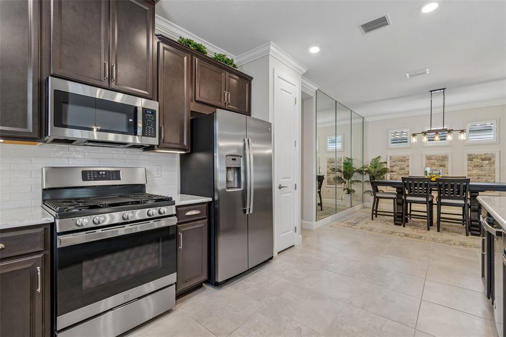 A kitchen with dark wood cabinets, stainless steel appliances, and an adjacent dining area — 4534 GAROFALO ROAD, WESLEY CHAPEL, FL