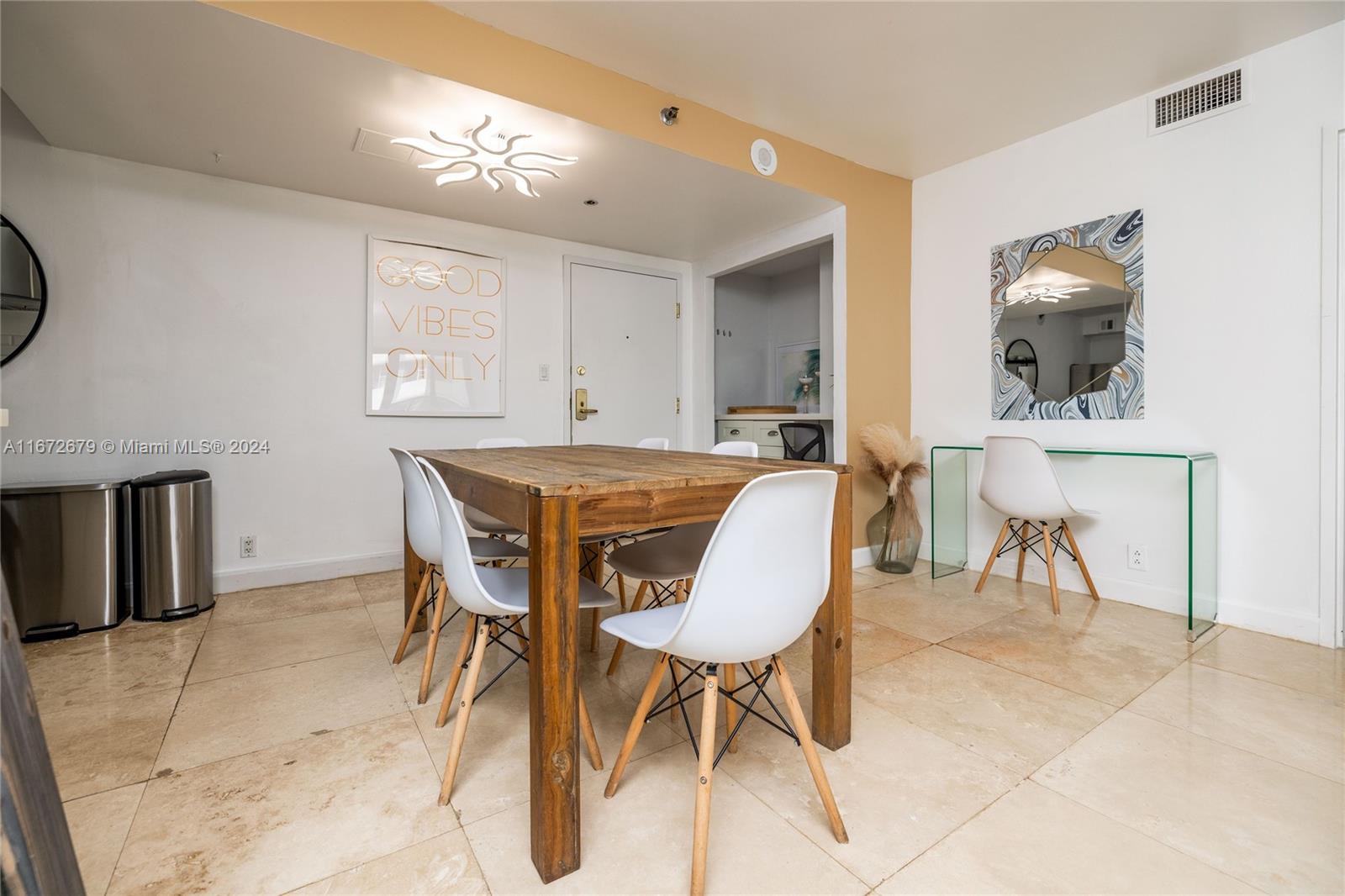 A dining area features a wooden table, white chairs, a glass console table, and tile flooring — 5225 Collins Ave # 1114, Miami Beach FL 33140, MIAMI BEACH, FL