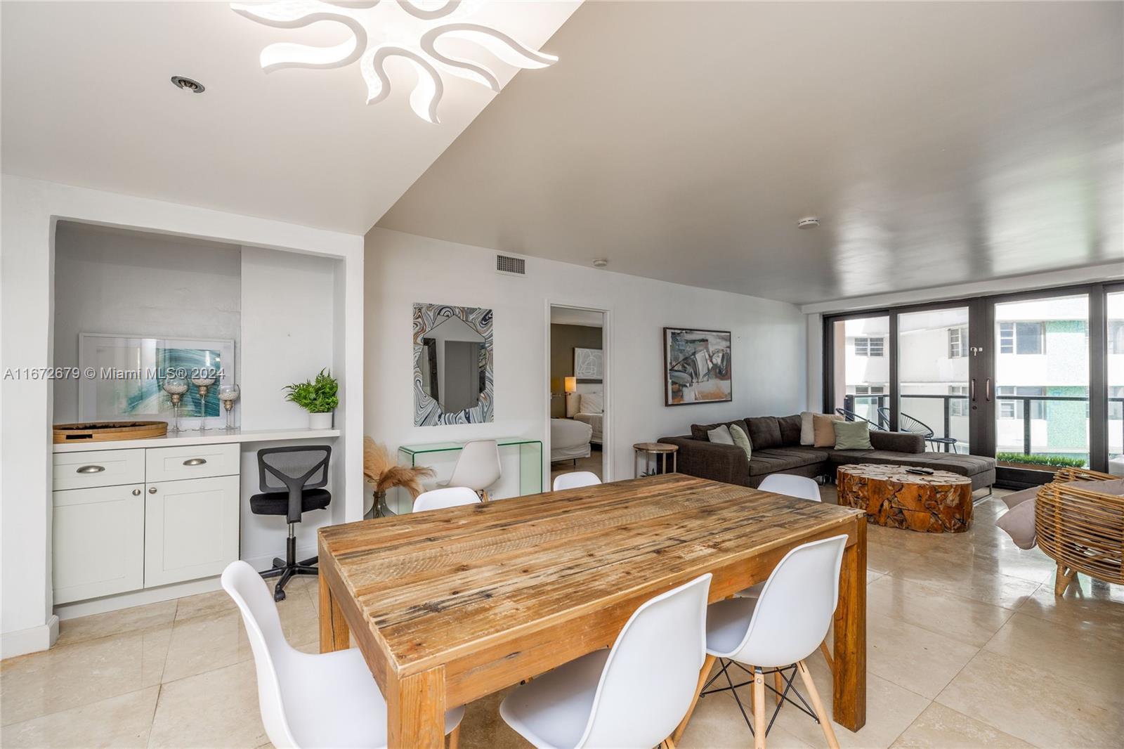 An open-plan living and dining area features a wooden table, white chairs, and tile flooring — 5225 Collins Ave # 1114, Miami Beach FL 33140, MIAMI BEACH, FL
