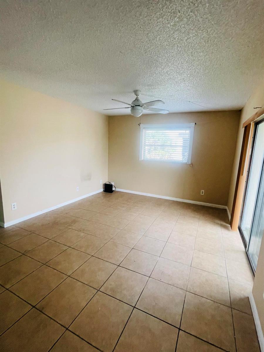 An empty room with tan walls, tiled flooring, a ceiling fan, and a sliding glass door — 420 S B Street # A4, FL 33460, FL