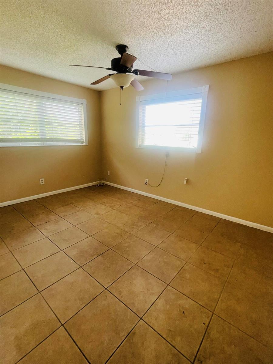 An empty bedroom with tan walls, tile flooring, a ceiling fan, and two windows — 420 S B Street # A4, FL 33460, FL