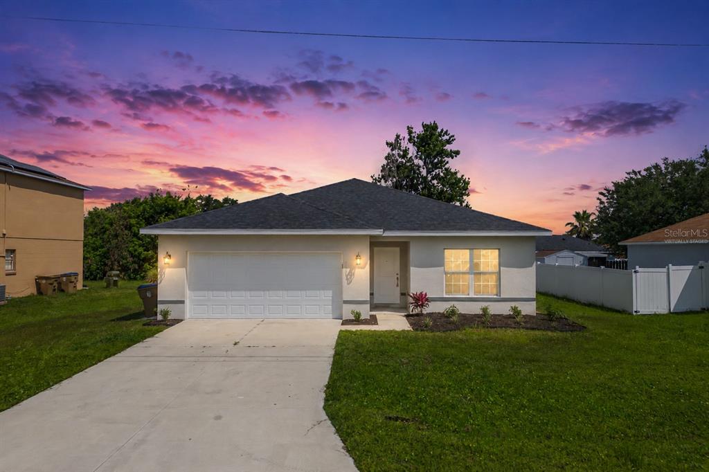 A single-story house with a white garage and exterior at sunset — 1109 MUNSTER COURT, KISSIMMEE, FL