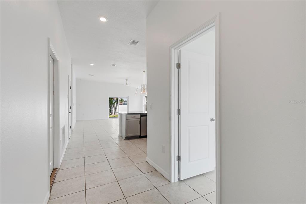 A hallway with tiled floors leads to an open kitchen and living area — 1109 MUNSTER COURT, KISSIMMEE, FL