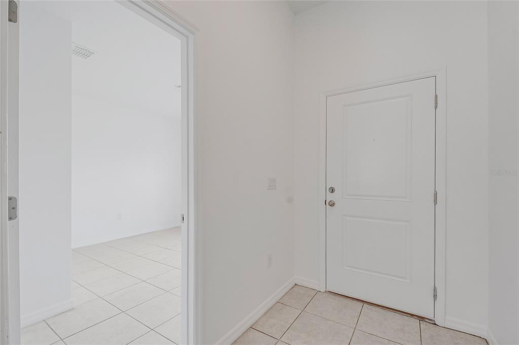 An interior view shows a white front door and a doorway leading to a tiled room — 1109 MUNSTER COURT, KISSIMMEE, FL