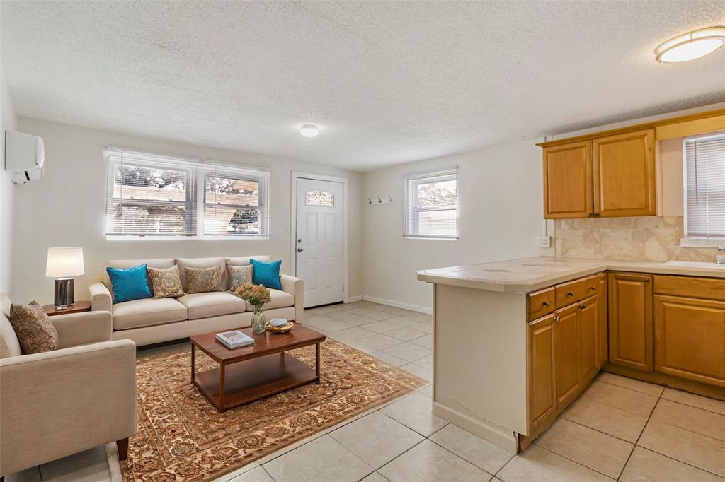 A living room with tile floors and a kitchen island opens to an exterior door — 809 ILLINOIS AVENUE, PALM HARBOR, FL