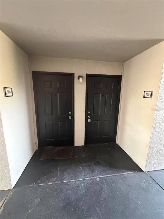 Two black apartment doors labeled 105 and 106 are set in a beige exterior hallway — 7605 PISSARRO DRIVE UNIT 13106, ORLANDO, FL