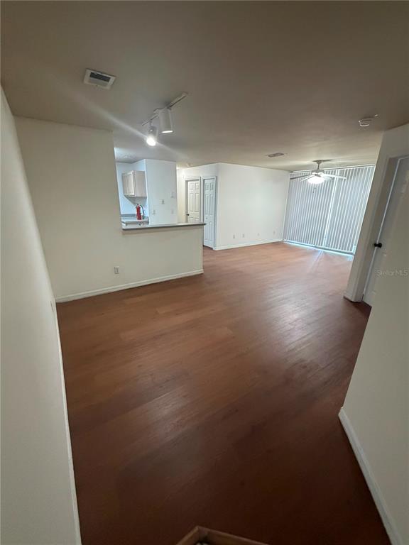 An open-concept living area with wood-look flooring and a kitchen with a breakfast bar — 7605 PISSARRO DRIVE UNIT 13106, ORLANDO, FL