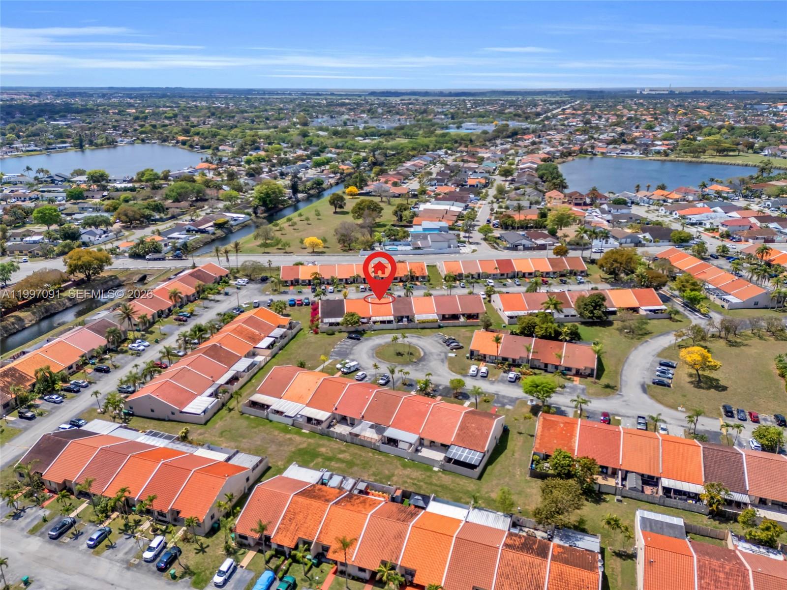 An aerial view shows a residential neighborhood with rows of townhouses featuring orange-tiled roofs — 6323 SW 147th Place Cir, Miami FL 33193, MIAMI, FL