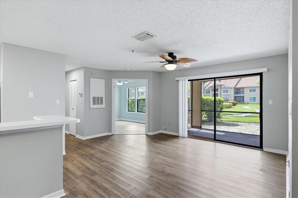 A living room with light gray walls, wood-look flooring, a ceiling fan, and sliding glass doors — 4057 CROCKERS LAKE BOULEVARD UNIT 16, SARASOTA, FL
