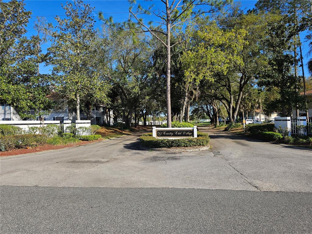 The entrance to Country Club Village features a paved road split by a landscaped sign — 8142 FAIRWAYS CIRCLE UNIT S204, OCALA, FL
