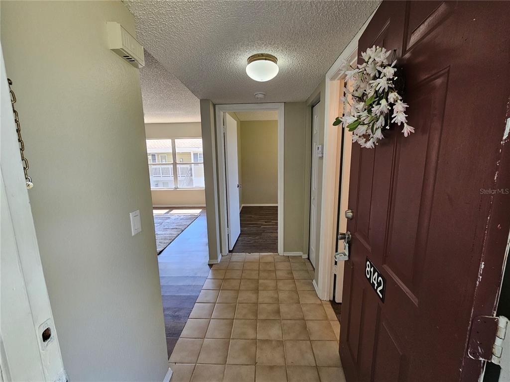 An entryway with tile flooring leads to a living area and a hallway with wood-look floors — 8142 FAIRWAYS CIRCLE UNIT S204, OCALA, FL